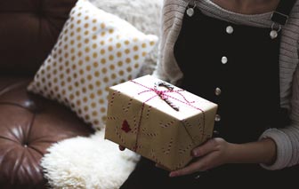 A girl in sweatshirt and jumper holding a gift.