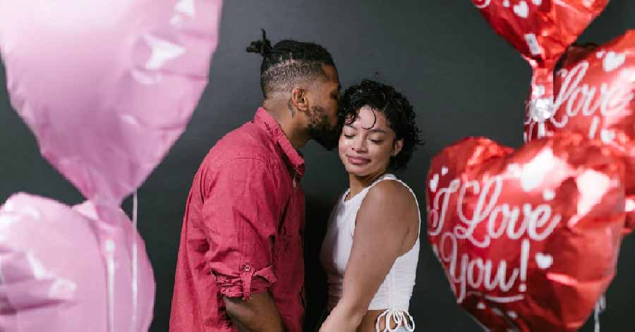 man kissing a woman, valentine’s balloons around them