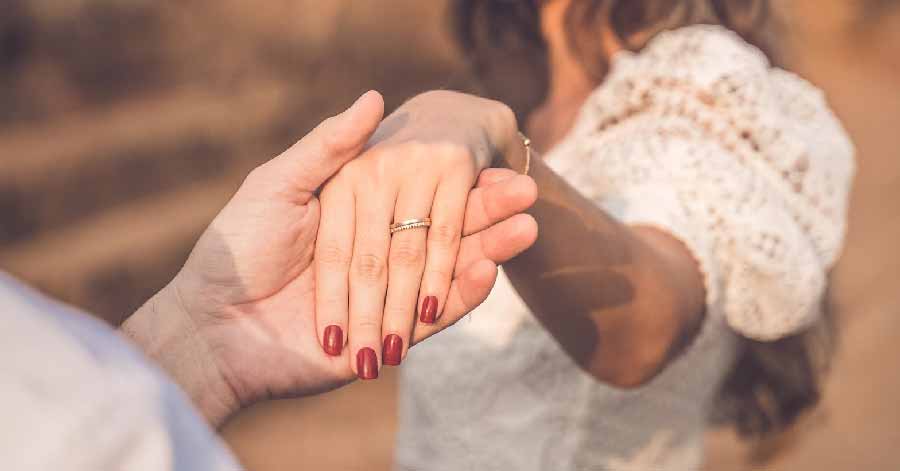 man holding woman’s hand with engagement ring